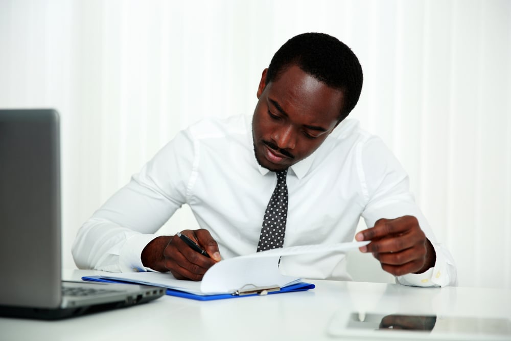 African man signing document in office